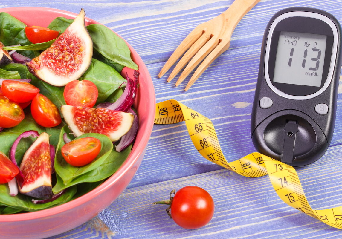 Fruit and vegetable salad, glucometer with result of measurement sugar level and tape measure, concept of diabetes, diet, slimming, healthy lifestyles and nutrition